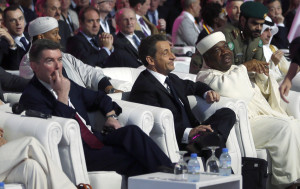 Former French President Sarkozy sits as Attias, founder and president of Cecilia Attias Foundation for Women, and Sarkozy's ex-wife, walks past during official opening ceremony of Doha GOALS forum in Doha